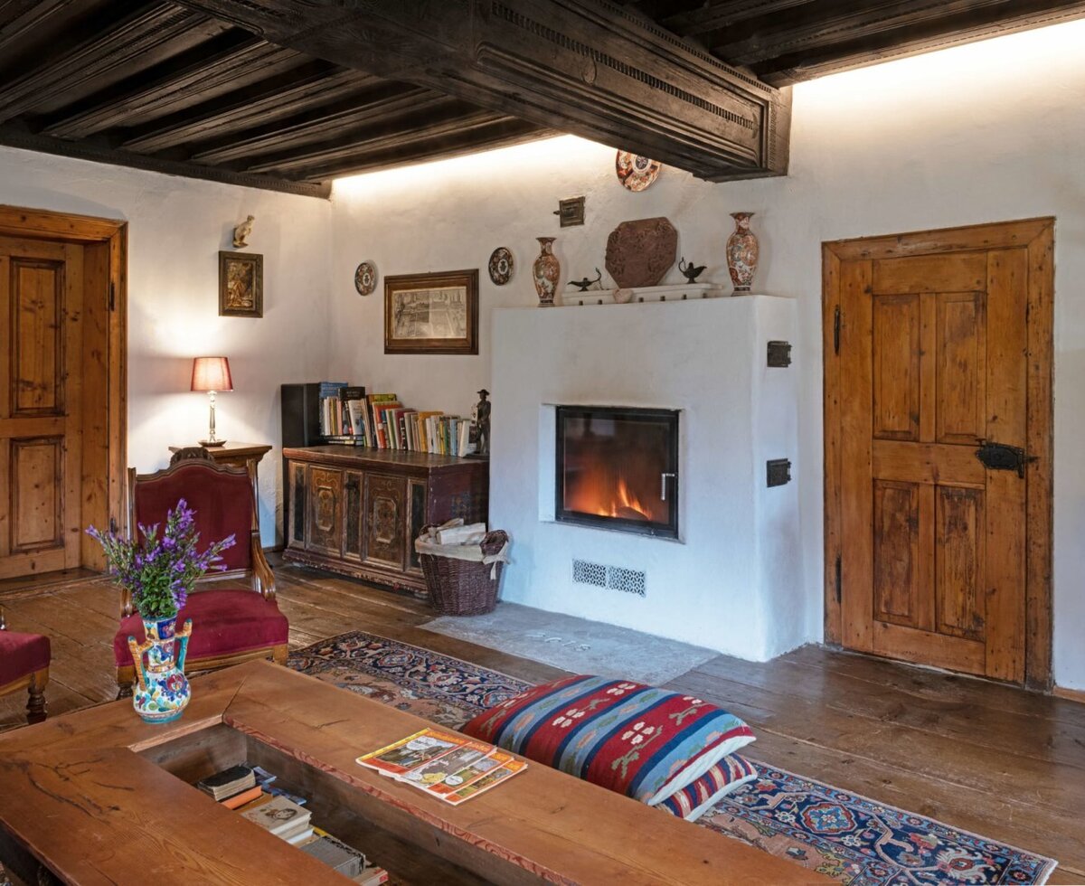 Der Salon in der Hinterbreiteneben mit Kamin, Holzbalkendecke, Holzboden und traditionellen Möbeln.