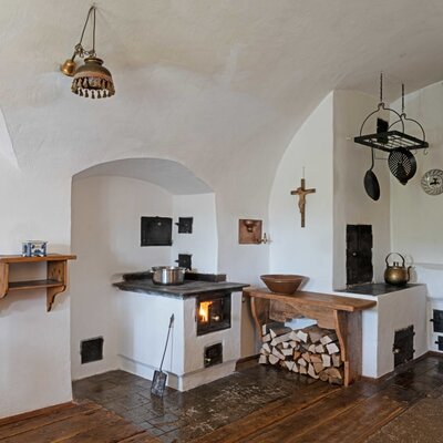 Traditioneller Küchenbereich des Ferienhauses Hinterbreiteneben mit Holzofen, Brennholz und Holztüren.