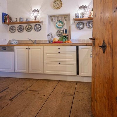 Küche in der Hinterbreiteneben mit weißen Schränken, Holztheke, Spüle, Geschirrspüler und Holzboden.