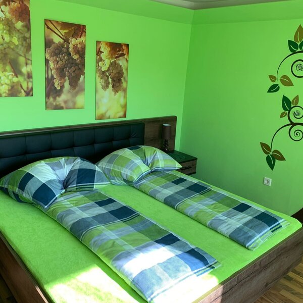 Doppelbett-Schlafzimmer im Bauernhof mit grünen Wänden, Traubenmotiven und einem Baumwandbild.