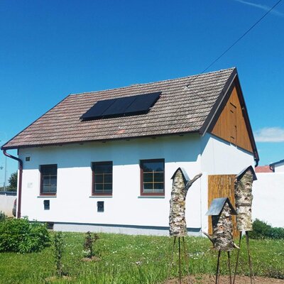 Außenansicht des Ferienhaus mit Solarpaneelen auf dem Dach und Insektenhotels im Garten.