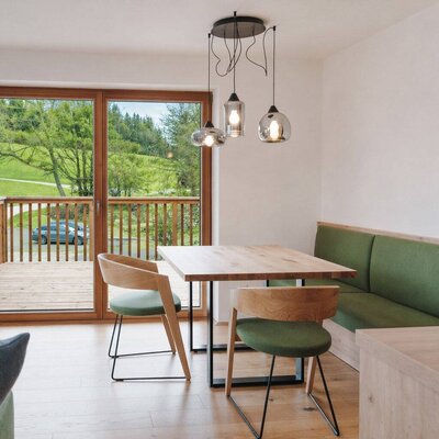 Einladender Essbereich des Landhofs mit einer modernen Sitzecke aus Holz und direktem Zugang zum sonnigen Balkon.