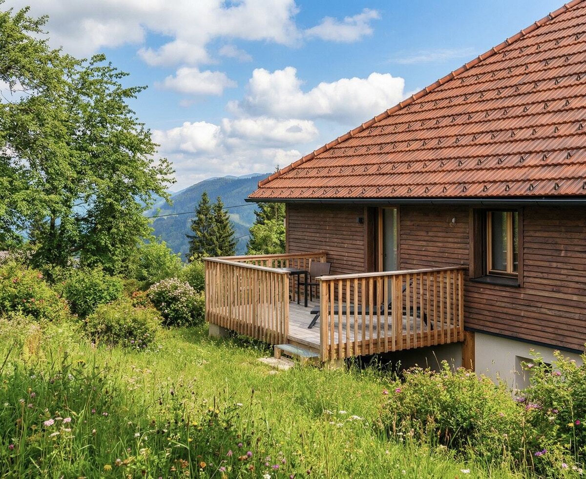Eine sonnige Holzterrasse am Landhof mit einem einladenden Sitzbereich und weitem Blick auf die idyllische Berglandschaft.