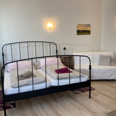 Schlafzimmer im Bauernhof mit Doppelbett, Schlafsofa und zwei Nachttischen.