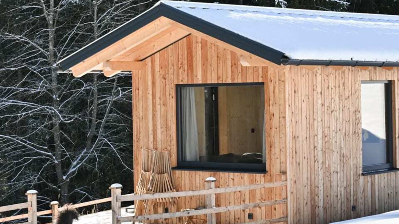 Das charmante Tiny House in einer verschneiten Winterlandschaft direkt am Waldrand.