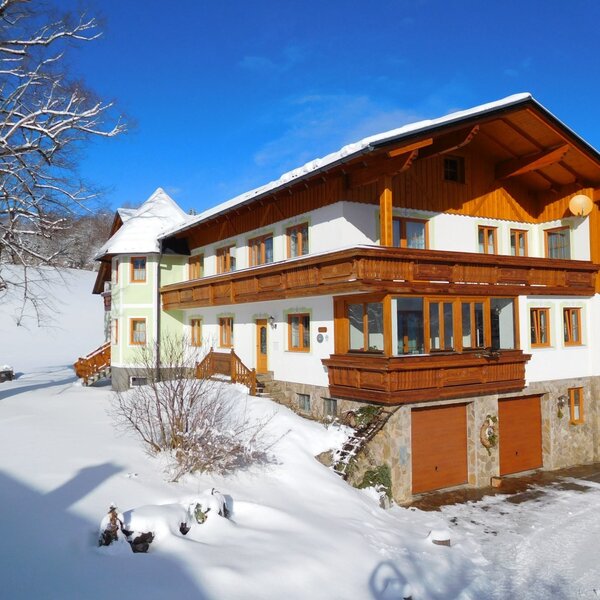Der Bauernhof im Winter, mit schneebedecktem Außengelände und traditionellen Holzbalkonen.