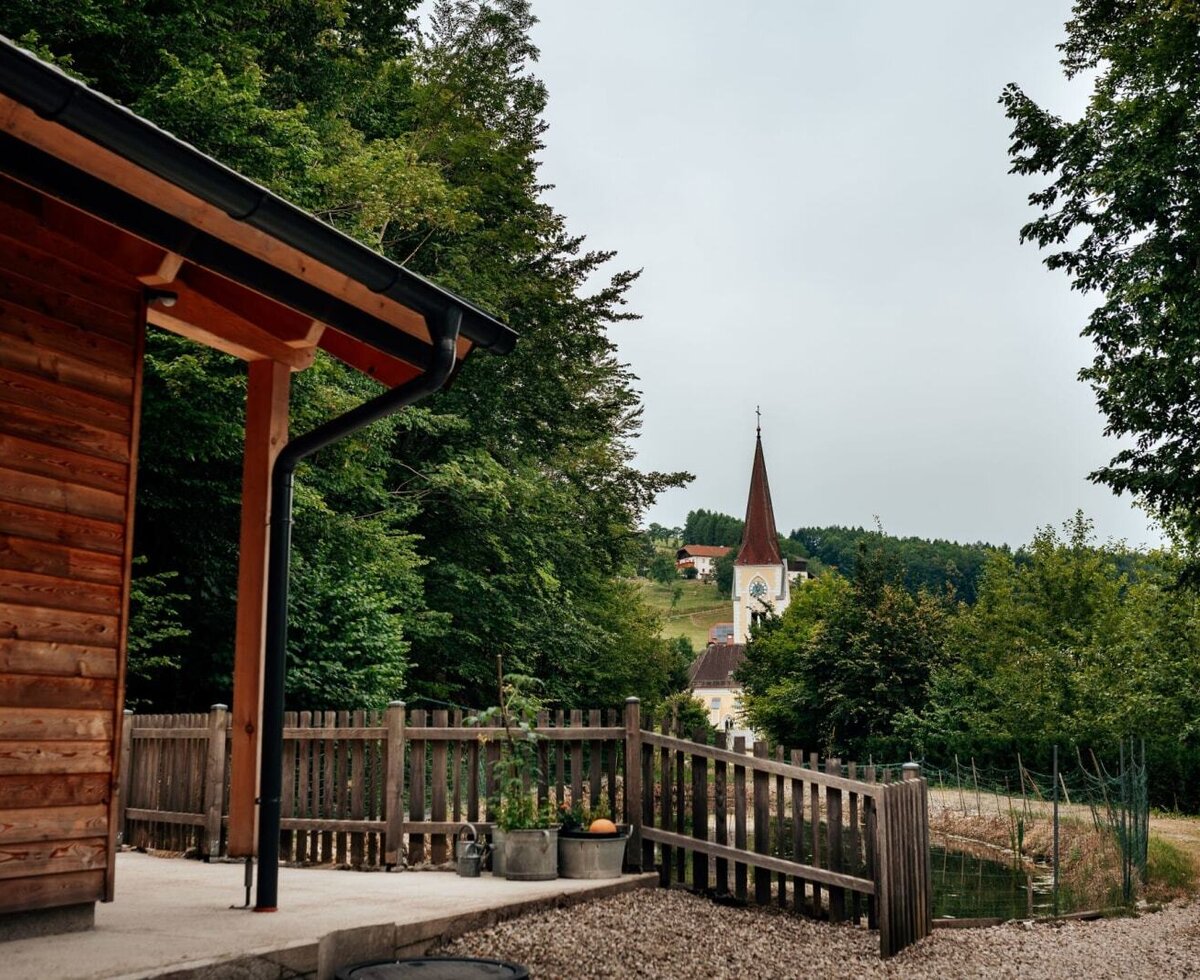 Die idyllische Außenanlage, einem kleinen Teich und Ausblick auf den nahen Kirchturm.