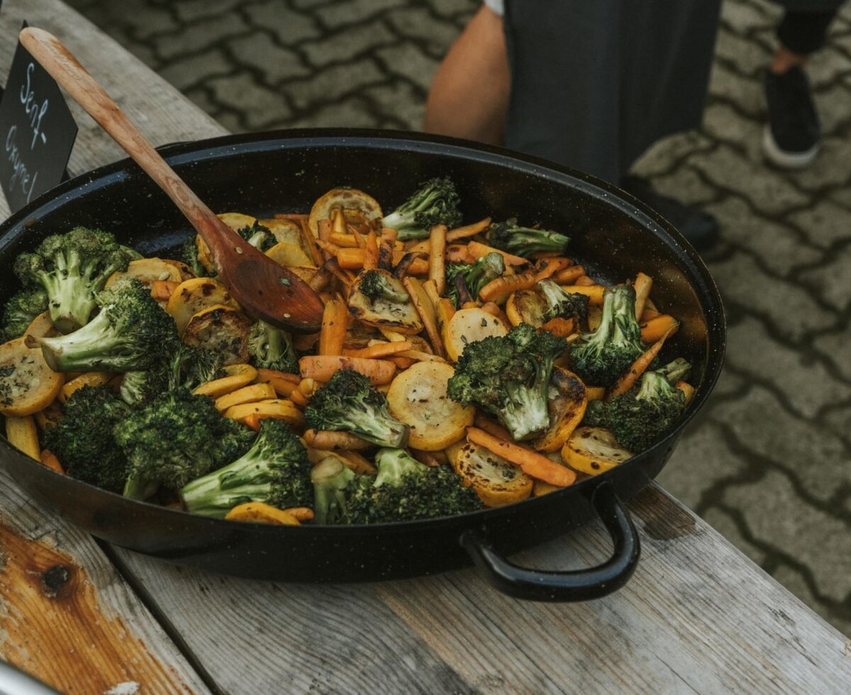 Große Pfanne mit geröstetem Brokkoli, Karotten und Zucchini, serviert auf dem Bauernhof.