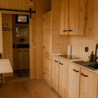 Eine gemütliche Küchenzeile aus hellem Holz im Bauernhof mit einem praktischen Essplatz und modernen schwarzen Armaturen.
