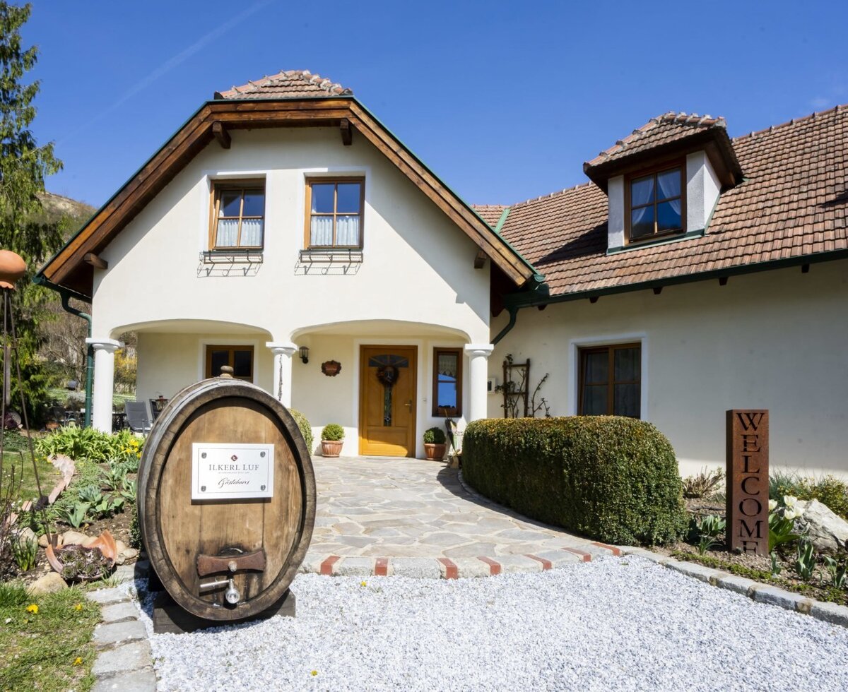 Der Eingangsbereich des Hofs mit einer gelben Tür, Säulen und einer Kiesauffahrt zum Gästehaus.