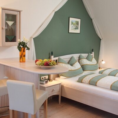Schlafzimmer im Hof mit Doppelbett, einer Bartheke mit zwei Barhockern und Dachschräge.