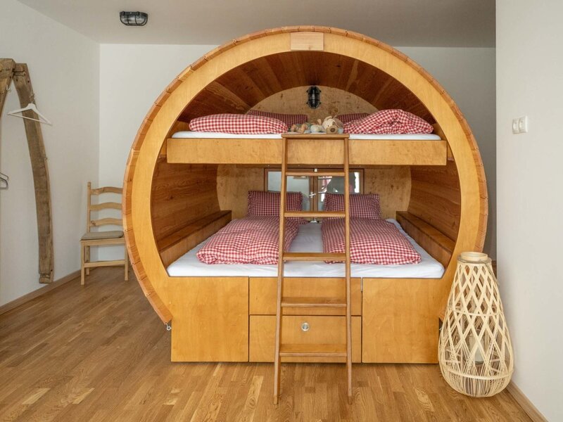 Ein Etagenbett in einer der Weinfass-Suiten des Winzerhofs, mit Holzinterieur und rot-weiß karierter Bettwäsche.