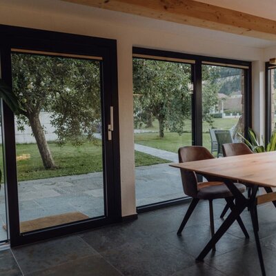 Essbereich im Chalet mit großzügigen Glasfronten und Blick auf den Obstgarten.
