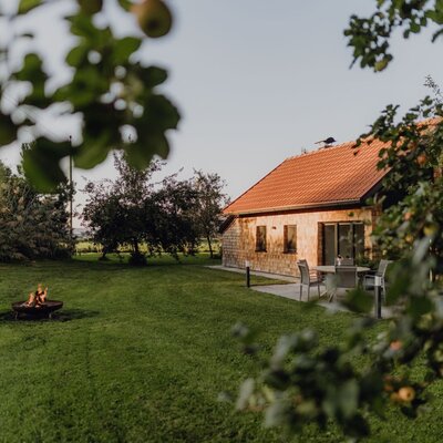 Das einladende Chalet des Bauernhofs im idyllischen Obstgarten mit einer gemütlichen Feuerschale und Sitzgelegenheiten im Freien.