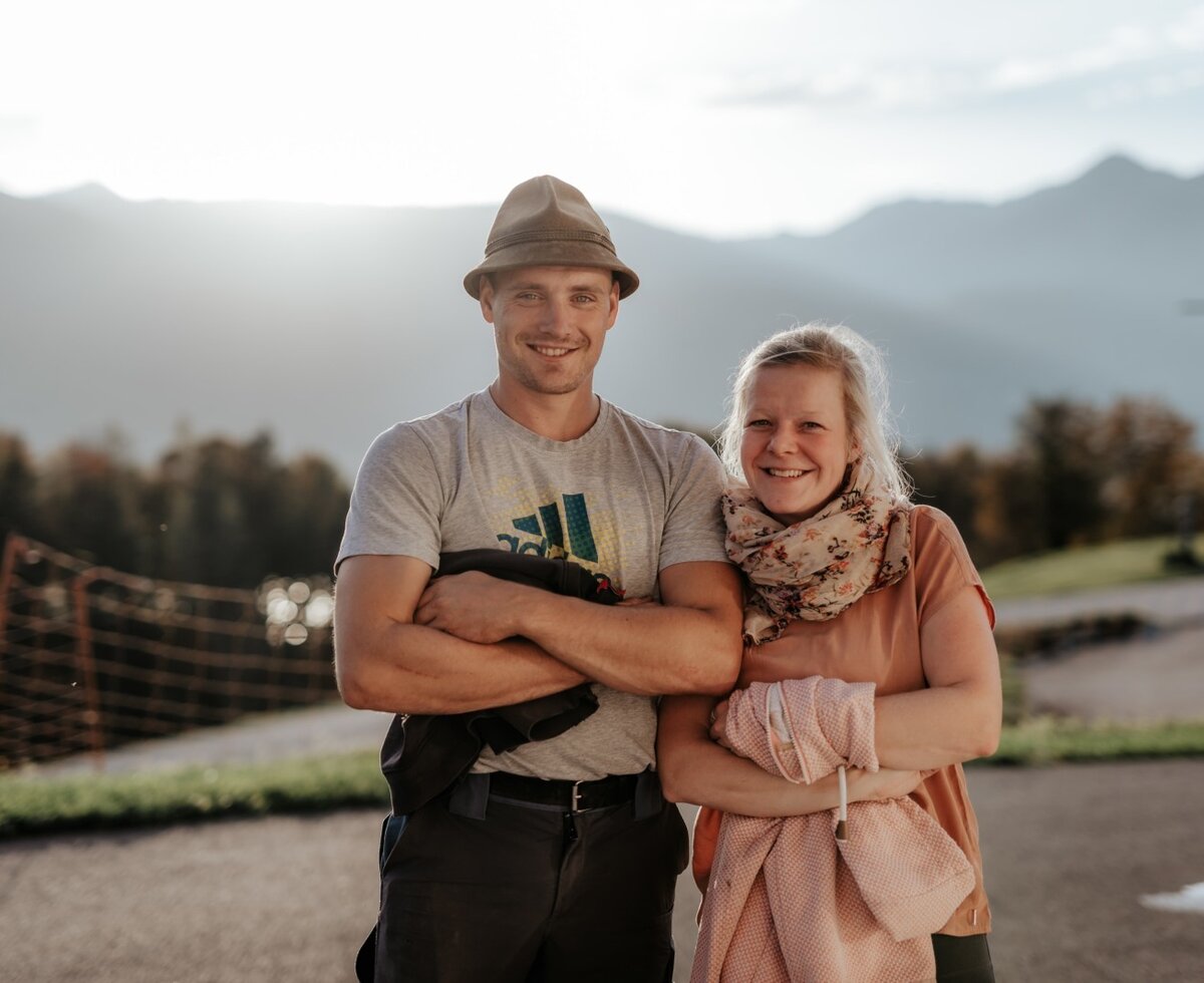 Die Gastgeber des Bauernhofs vor dem Bergpanorama.