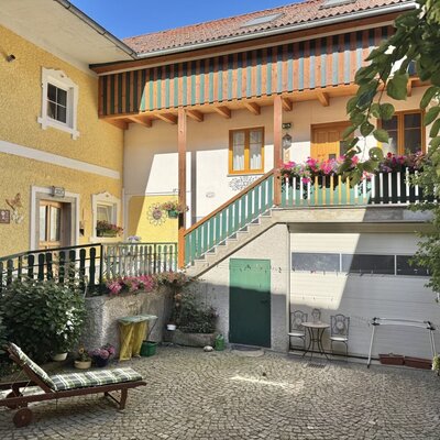 Außenansicht des Bauernhofs mit gepflastertem Innenhof, Sonnenliege und der Radgarage.