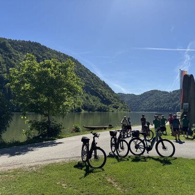 Fahrräder und eine Gruppe von Radfahrern am Seeufer, was die Radfreundlichkeit des Bauernhofs mit seiner Radgarage unterstreicht.