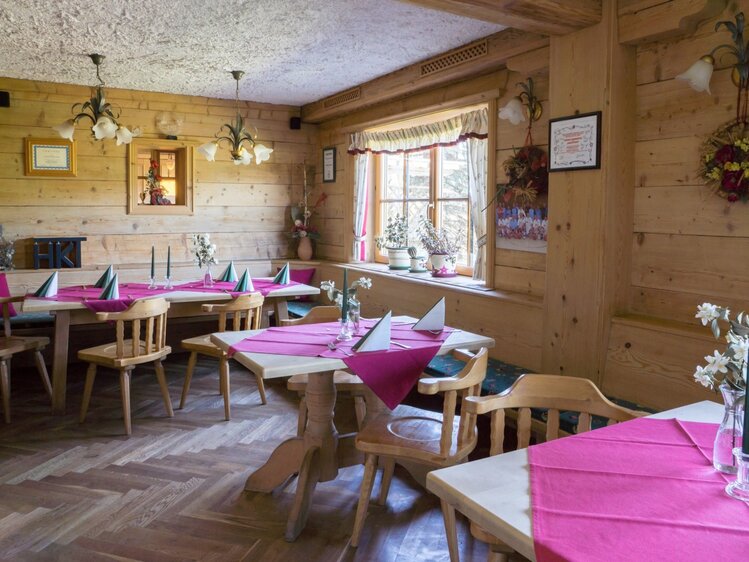 Der Gastraum im Bauernhof mit Holzeinrichtung und für Gäste gedeckten Tischen.