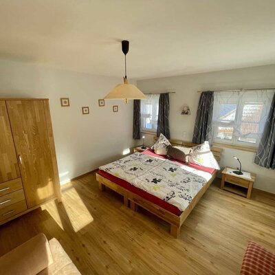 Schlafzimmer im Bauernhof mit Doppelbett, zwei Nachttischen mit Lampen und einem Holzschrank.