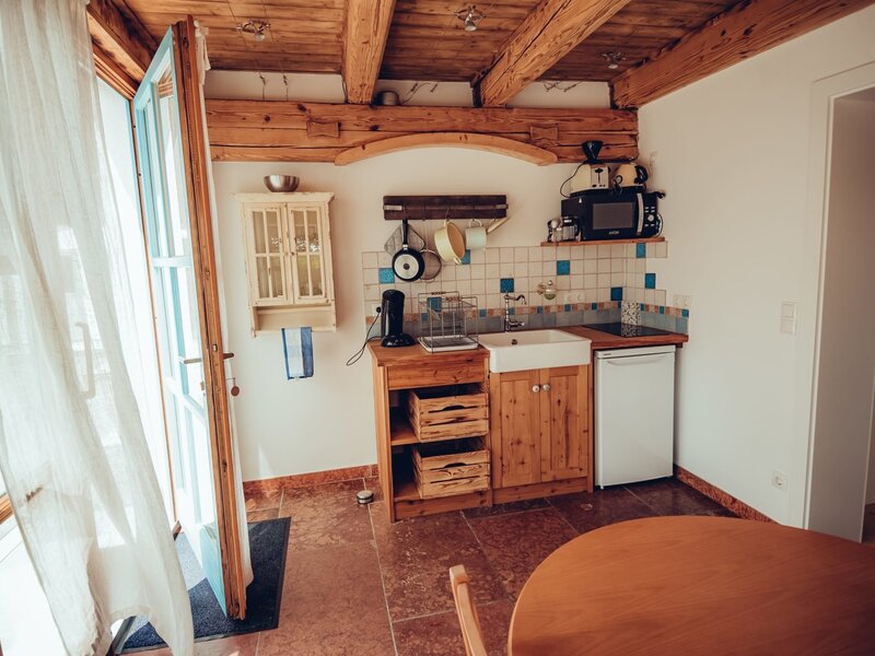 Die Küche im Bauernhof verfügt über Holzbalken, eine Spüle, ein Kochfeld, eine Mikrowelle, einen Kühlschrank sowie einen Esstisch und bietet direkten Zugang nach draußen.