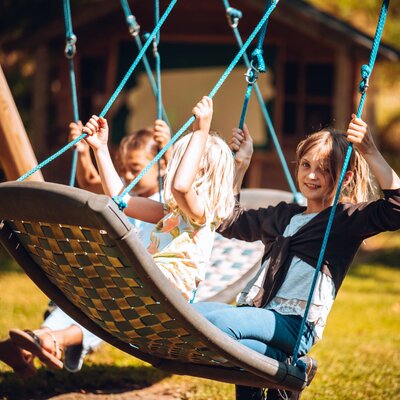 Kinder spielen auf der Nestschaukel im Garten des Bauernhofs.