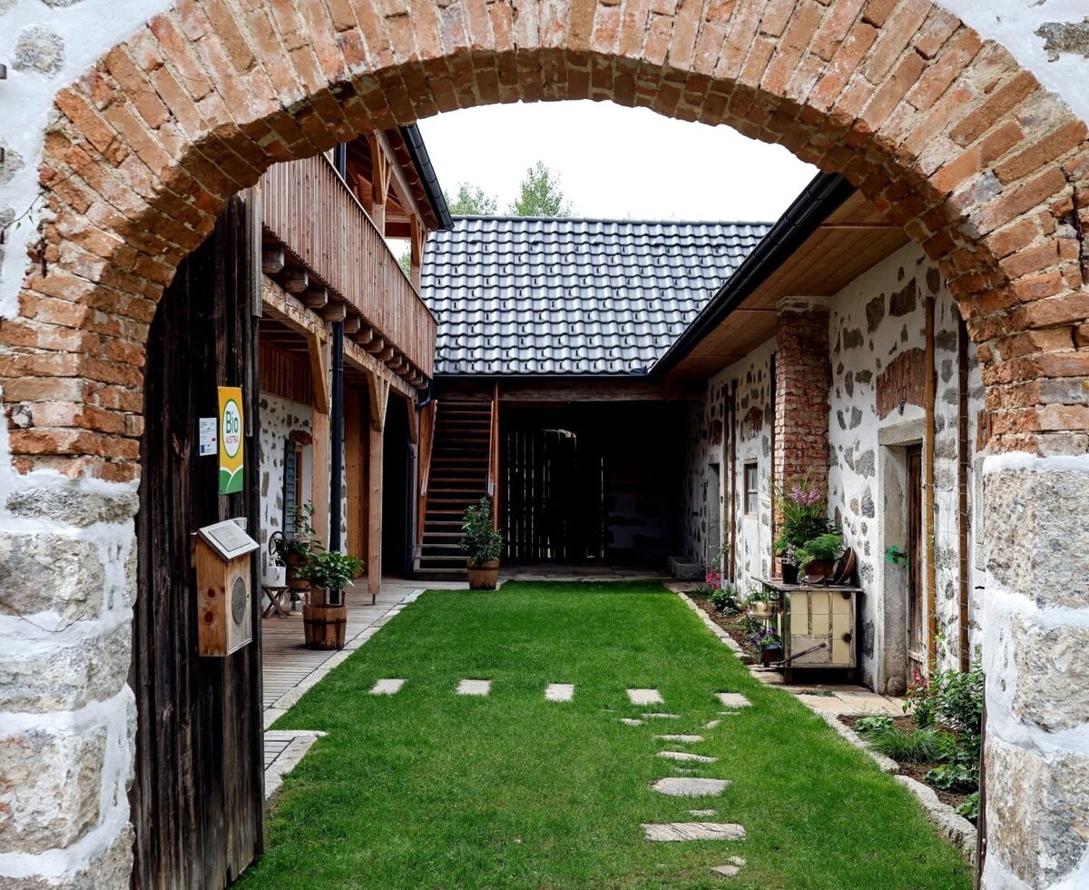 Unser einladender Innenhof, mit historischem Ziegelbogen und charmanter Steinblossfassade.