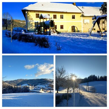 Der Bauernhof im Winter mit schneebedecktem Spielplatz, Schaukel und der umliegenden Winterlandschaft.