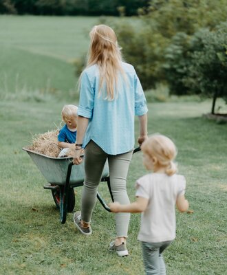 Eine Familie genießt eine Heufahrt in der Schubkarre auf dem Gelände des Bauernhofs.