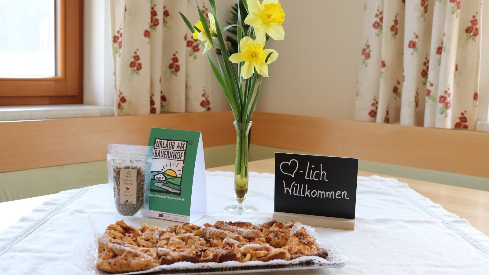 Ein herzlicher Willkommensgruß auf dem Bauernhof mit frischem Gebäck, Narzissen und Informationen für die Gäste.