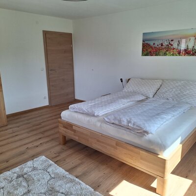 Doppelzimmer im Bauernhof mit Doppelbett aus Holz, Kleiderschrank, Nachttischen und Holzboden.