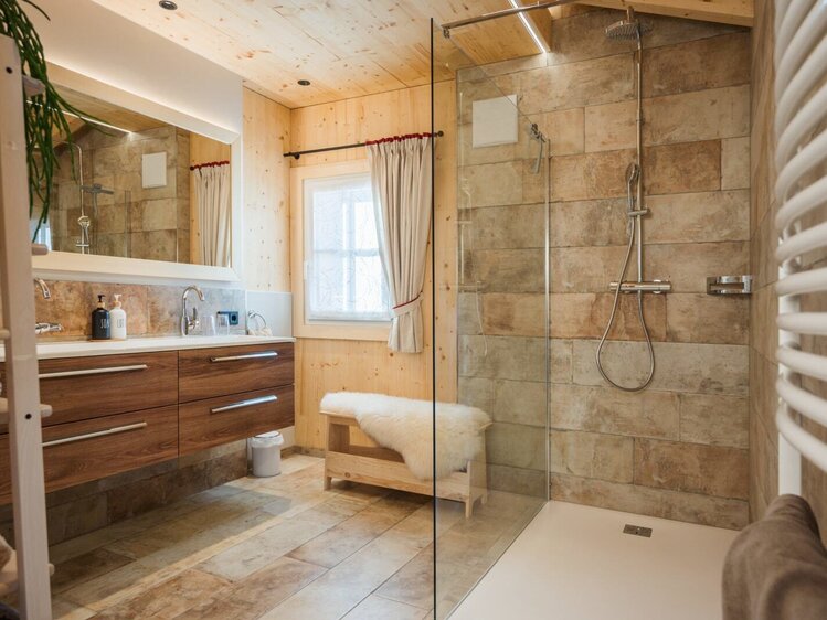 Das Badezimmer im Hof ist mit einer begehbaren Dusche, einem Waschtisch mit Doppelwaschbecken, Holzwänden und einem Handtuchwärmer ausgestattet.