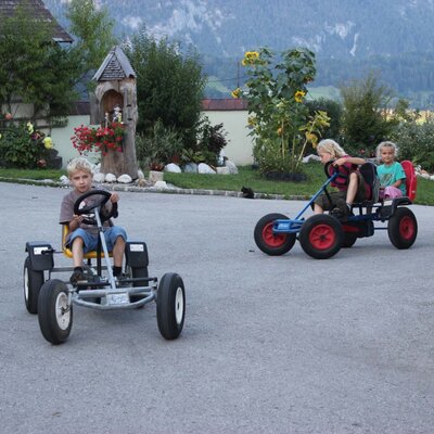 Kinder fahren Tret-Gokarts auf dem Gelände des Bauernhofs.