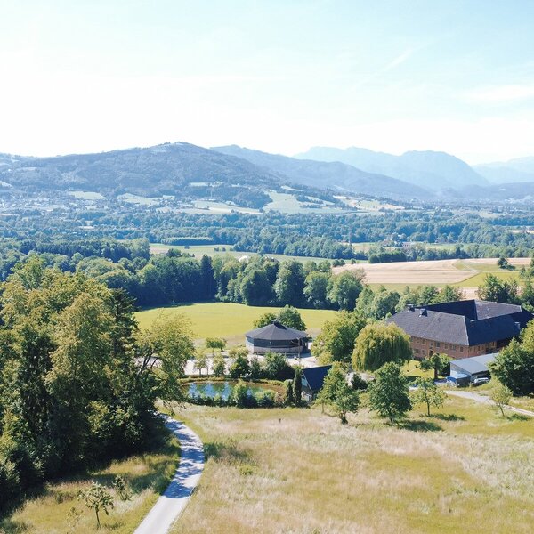 Malerischer Blick auf den von Wiesen und Wäldern umgebenen Bio-Bauernhof mit den gemütlichen Appartements im oberösterreichischen Alpenvorland.