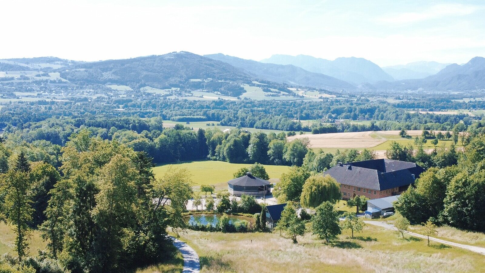 Malerischer Blick auf den von Wiesen und Wäldern umgebenen Bio-Bauernhof mit den gemütlichen Appartements im oberösterreichischen Alpenvorland.