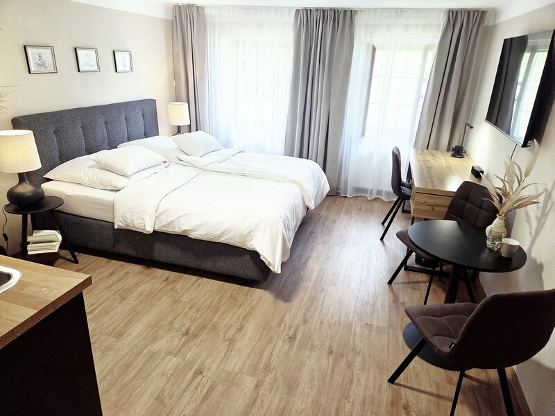 Das einladende Schlafzimmer des Apartments mit einem komfortablen Doppelbett, Holzboden und einer gemütlichen Sitzecke.