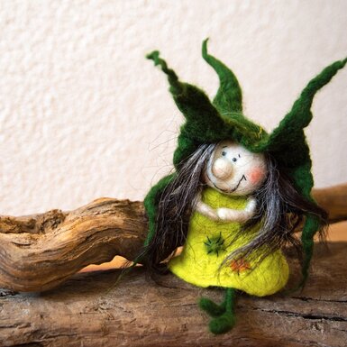 Eine dekorative Filz-Wichtelfigur mit grünem Gewand und Hut als Teil der Ausstattung des Bauernhofs.