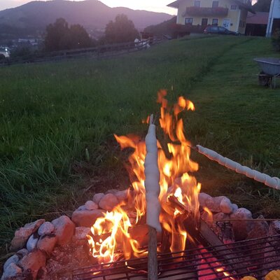Lagerfeuer mit Stockbrot und gegrilltem Mais im Garten des Bauernhofs.