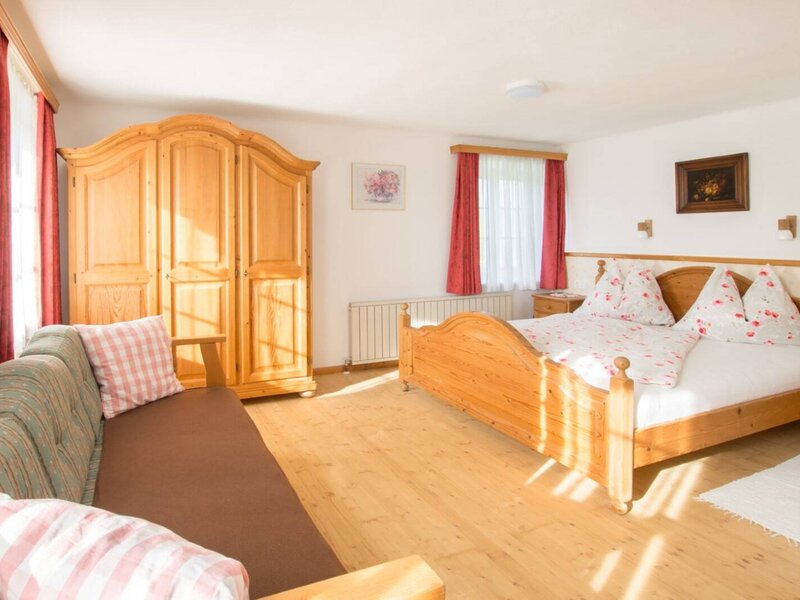 Doppelzimmer im Bauernhof mit Doppelbett, Holzkleiderschrank und Schlafsofa.
