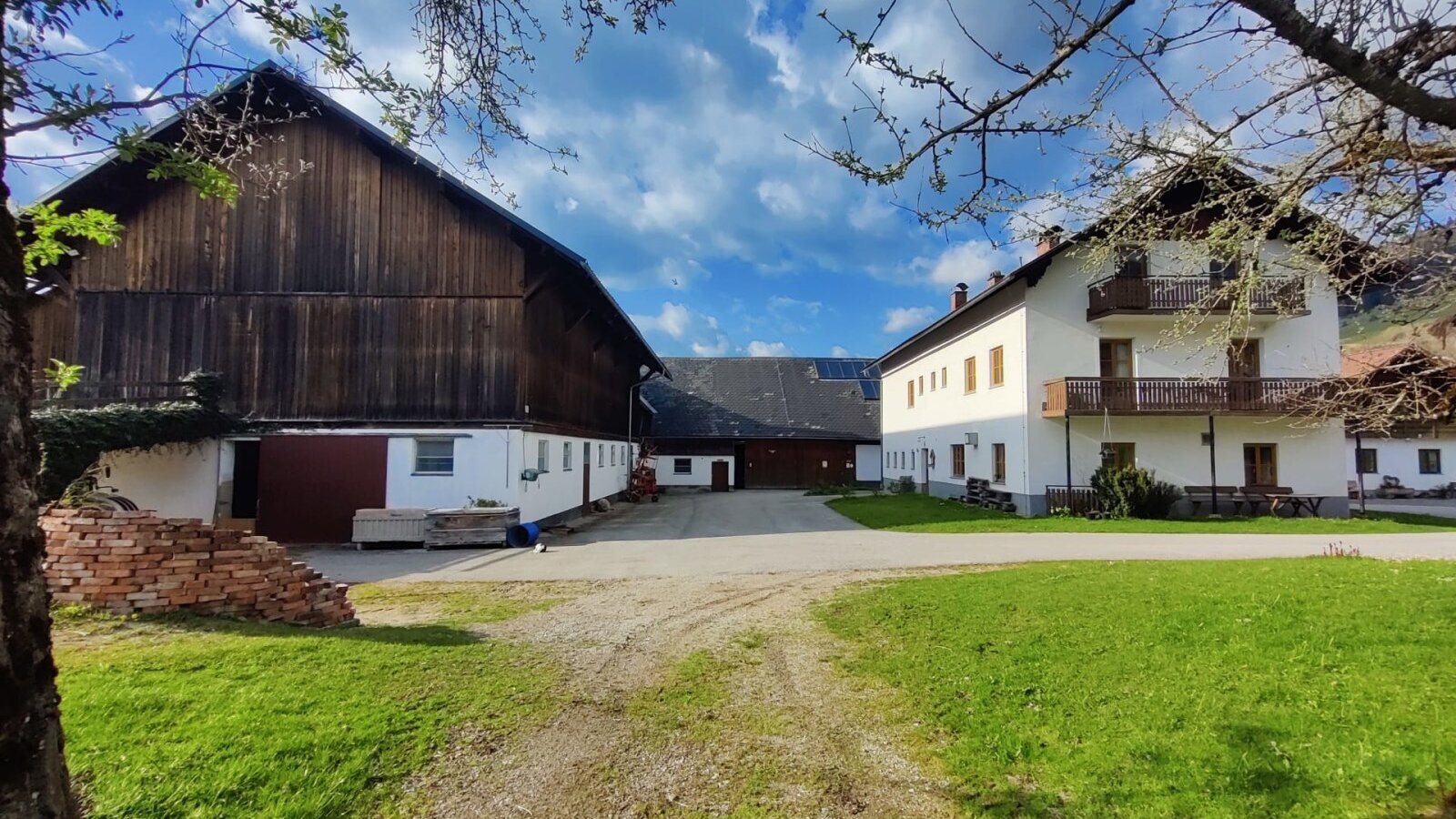 Außenansicht des Bauernhofs mit Stall und Wohngebäude.
