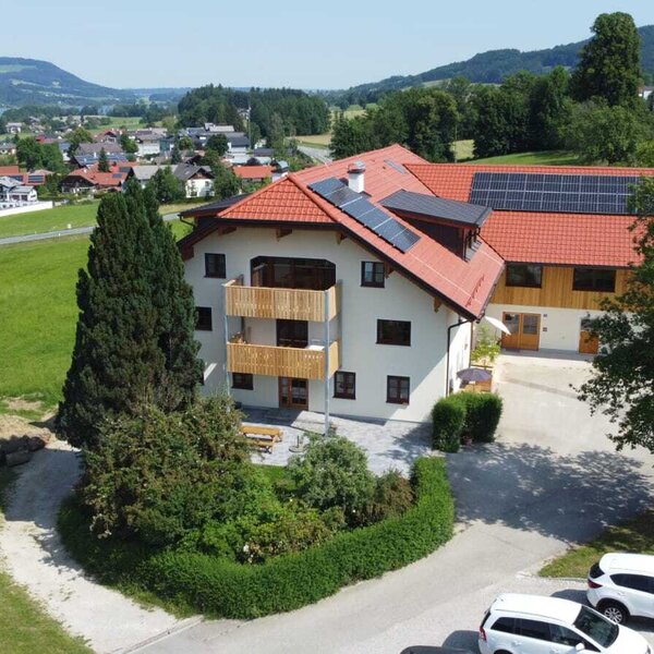 Der Bauernhof mit Balkonen und Solaranlagen auf dem Dach bietet einen Blick auf den See und die Hügellandschaft.