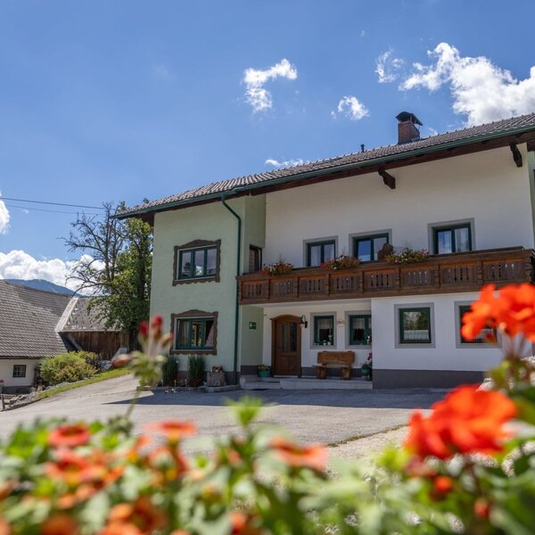 Unser Ferienhof Mittermair mit traditionellem Holzbalkon und blühendem Blumenschmuck