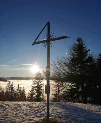 Gipfelkreuz von der Freidhofbergalm mit Blick auf die umliegenden Berge.