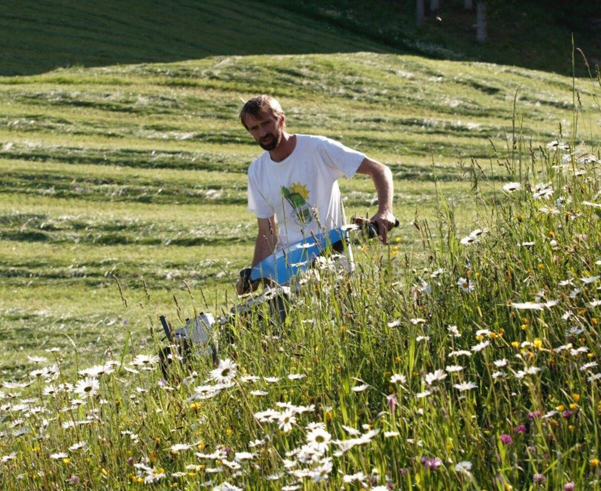 Ein Mitarbeiter mäht die Blumenwiesen des Bio-Bauernhofs.