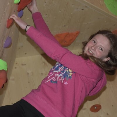 Indoor-Kletterwand mit farbigen Griffen für junge Gäste auf dem Bauernhof.