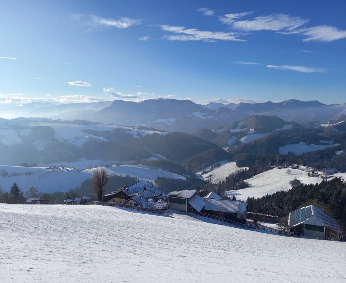 Winterlandschaft mit dem Bauernhof und schneebedeckten Bergen