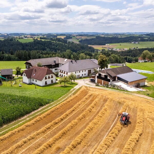 Luftaufnahme des Bauernhofs mit seinen Gebäuden, einem Traktor auf den Feldern und einem Spielplatz. ©TVB Mühlviertel Berlinger Justin