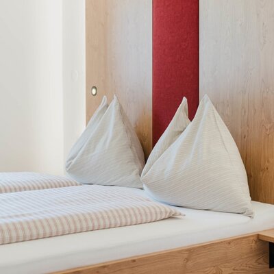 Ein gemütliches Doppelbett mit einladender, gestreifter Bettwäsche und warmem Holz-Kopfteil auf dem Bauernhof.