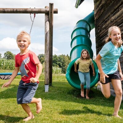 Der abwechslungsreiche Spielplatz des Bauernhofs umfasst eine Röhrenrutsche und eine Nestschaukel.
