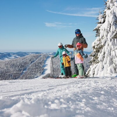 Familien-Skifahren in der verschneiten Berglandschaft, eine der Winteraktivitäten, die Sie vom Bauernhof aus erleben können.
