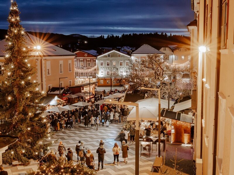 Ein stimmungsvoller Weihnachtsmarkt auf dem nahegelegenen Dorfplatz mit festlicher Beleuchtung und einem großen, geschmückten Tannenbaum Mondsee.